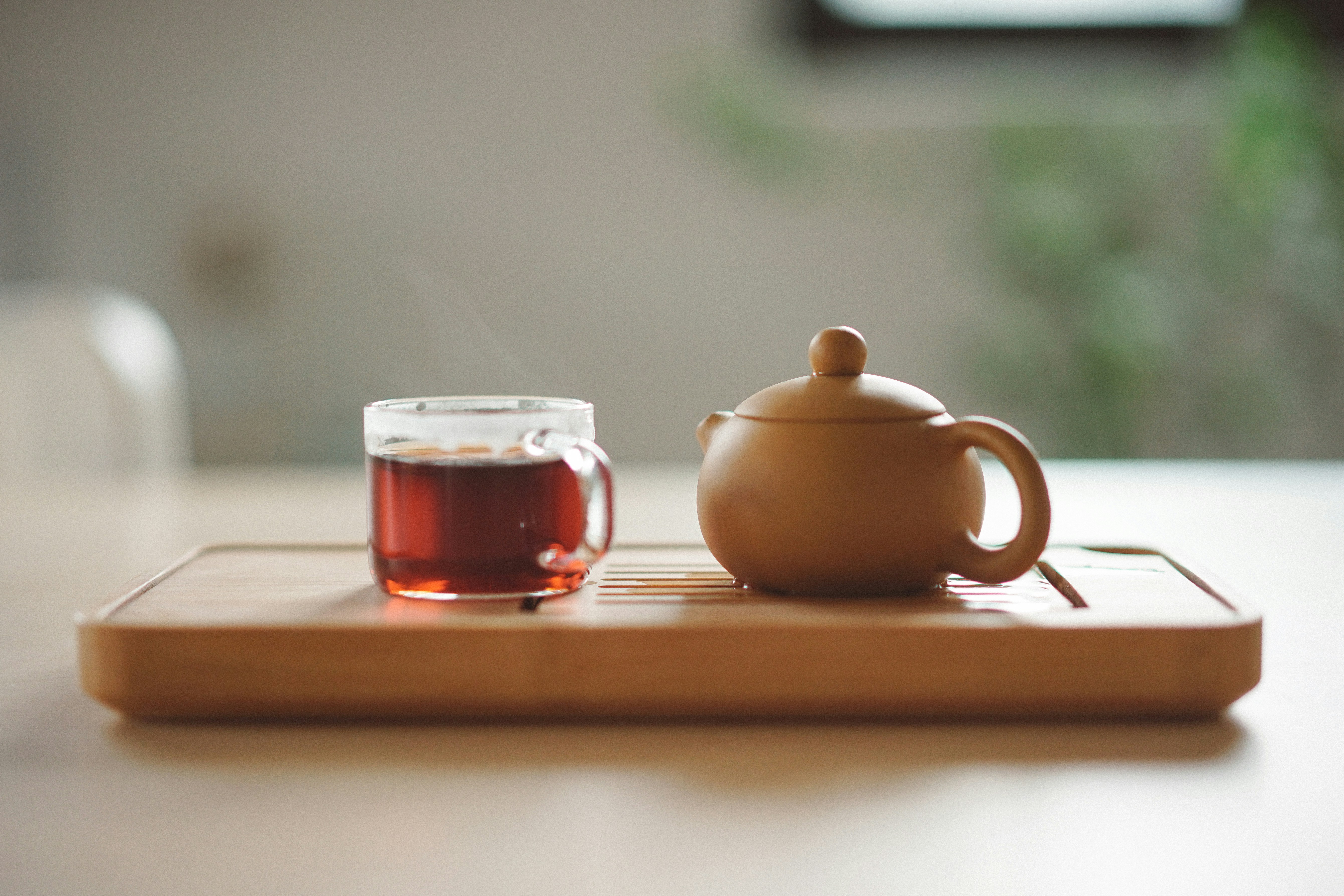 clear glass cup with tea near brown ceramin teapot